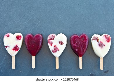 Frozen popsicle in heart-shape with fresh raspberries