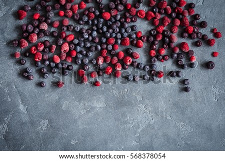 Frozen raspberry, blueberry, cranberry on grunge background. Frozen fruit. Flat lay, top view, copy space