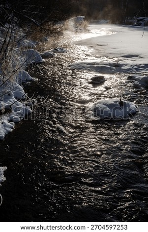 frozen river currents, snowcovered stream with icy patches and submerged stones creating turbulence, frozen waterway with scattered ice fragments and wet rocks generating gentle moving flows