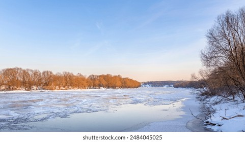 A frozen river flows through a winter landscape, the ice reflecting the clear blue sky above. Bare trees line the banks, their branches reaching towards the sunlight.
 - Powered by Shutterstock