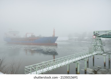Frozen river, large cargo ship, swing bridge. Snow, thick fog. Concept winter urban landscape. Transportation, nautical vessel, global communications, industry, logistics