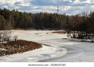 A frozen river in a snowy landscape with an industrial tower in the background. - Powered by Shutterstock