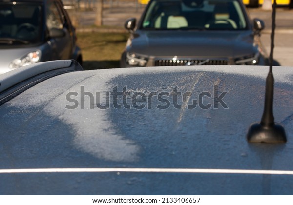 frozen roof of a car in the sun, defrosting and \
melting in the sun