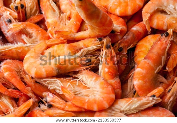 Frozen shrimp. Seafood\
on the counter. Fish market. Close-up shooting of seafood. Box with\
shrimp. Photo of shrimp in the supermarket. Wholesale of fish. \
Peeled shrimp.
