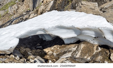 Frozen snow layer arching over a small creek