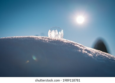 Frozen soap bubble with a beautiful pattern on the snow close up on a blurry background