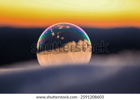 Frozen soapbubble in snow with sunset in background