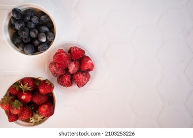Frozen strawberries, raspberries and blueberries covered with hoarfrost. When berries are frozen, vitamins are preserved. Top view. Copy space.