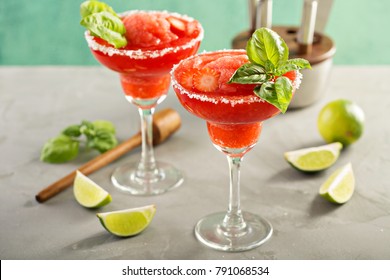 Frozen strawberry lime basil margarita in tall footed glasses