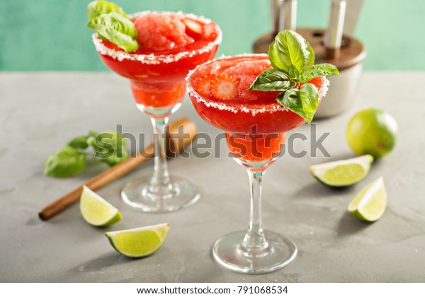 Frozen strawberry lime basil margarita in tall\
footed glasses