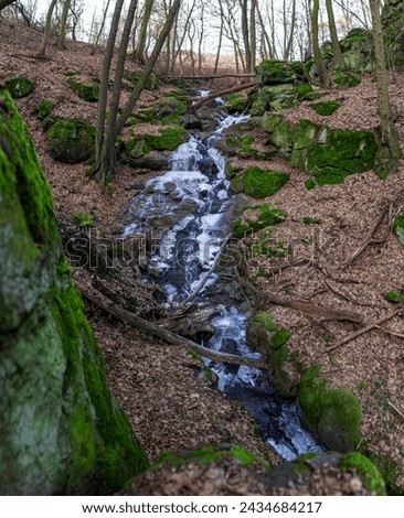 Frozen stream in the forest, ice in water, small waterfall in winter, Czech Highlands, Czech Republic