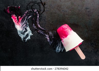 Frozen Summer Ice Lolly Made With The Pulp Of Fresh Strawberries Lying On A Dark Background With A Smear Of Melted Fruit And Ice Cream And Copyspace, Overhead View