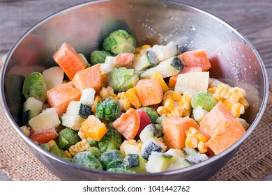 Frozen vegetables in bowl on wooden table background. Mixed vegetables in a bowl