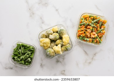 Frozen vegetables in containers , frozen cauliflower and asparagus beans, peas and corn, Brussels sprouts and carrots, mix of vegetables, top view, copy space - Powered by Shutterstock