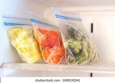 Frozen vegetables in plastic bags in freezer close up, front view