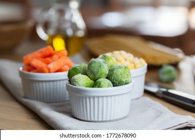 Frozen vegetables such as baby carrot and Brussels sprouts in the bowls on the kitchen table. Freezing is a safe method to increase the shelf life of nutritious foods