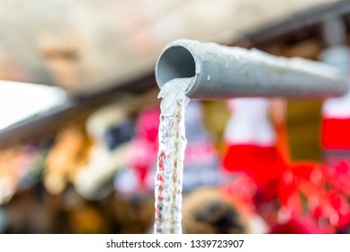 Frozen Water Flowing From The Roof Through A Plastic Pipe With A String Inside.