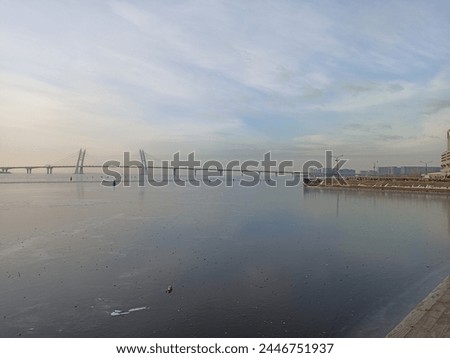 Frozen water on the river, panoramic view from the river bank to the bridge in winter, St. Petersburg
