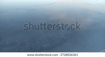 Frozen water surface with subtle ice patterns and soft winter light.
Calm frozen water surface with subtle ice textures and soft winter light, creating a minimal and abstract natural background with a tranquil atmosphere.