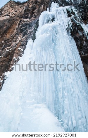 Frozen waterfall on rocky mountain in winter day.