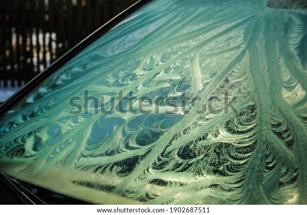 The frozen window of a car in cold winter day.\
Frost pattern. Selective\
focus