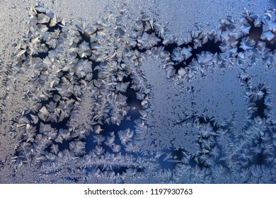 Frozen winter window. A beautiful pattern of glistening snowflakes on a frosted glass. Christmas background.