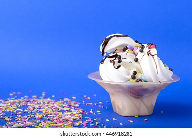 Frozen Yogurt With Chocolate And Chocolate Candy Topping On Blue Background With Rainbow Sprinkles