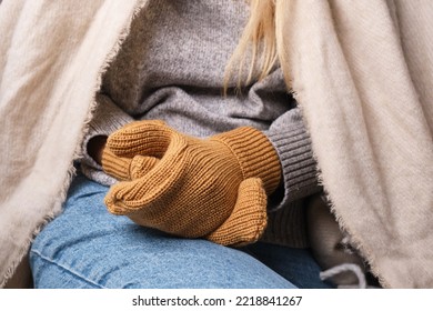 Frozen. A Young Woman Sits On The Floor In An Apartment In A Warm Sweater, Plaid And Mittens And Is Shivering From The Cold.