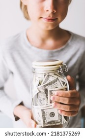 Frugal caucasian teenager boy is holding glass jar piggy bank with money dollars in his hands. Kid save money Saving money for education. Teaching child financial literacy with money Childhood - Shutterstock ID 2181375269