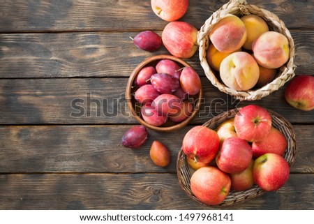 Fruit in baskets on a wooden table. Apples, peaches, plums. Rustic style