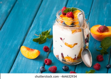 Fruit and berries dessert in a mason jar on blue table. Fruit salad with yogurt or sour cream. - Powered by Shutterstock