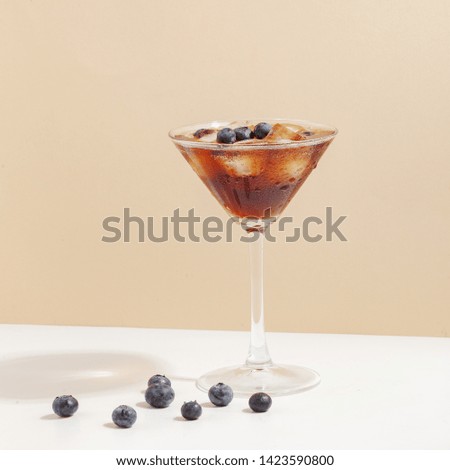 Fruit berry drink in a glass with ice on a colored background.