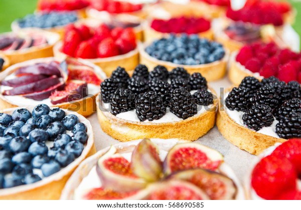 Fruit and berry tarts dessert tray assorted.\
Closeup of beautiful delicious pastry sweets with fresh natural\
blackberries and figs. French Bakery catering. Filtered, shallow\
depth of field
