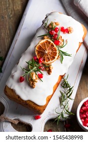 Fruit Cake Dusted With Icing, Nuts, Kernels Pomegranate And Dry Orange Close-up. Christmas And Winter Holidays Homemade Cake