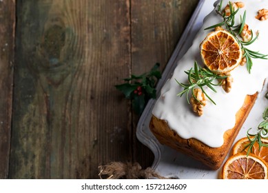 Fruit cake dusted with icing, nuts, kernels pomegranate and dry orange close-up. Christmas and Winter Holidays homemade cake