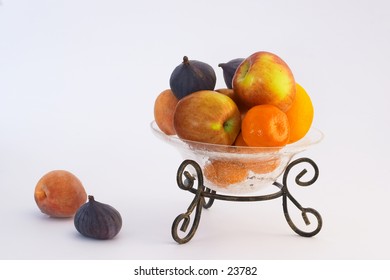 Fruit in a crackle-glass bowl on a metal stand.