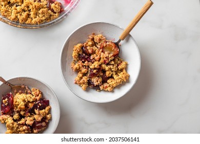 Fruit crumble. Plum crumble pie in plates with spoons on white marble table for tasty breakfast. Top view with copy space - Powered by Shutterstock