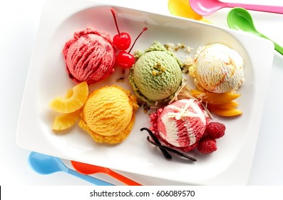 Fruit Ice Cream Scoops Overhead On White Plate With Pieces Of Fruits And Berries, Served With Several Colorful Spoons