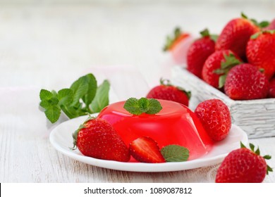 Fruit jelly with fresh strawberry. Healthy food. Strawberry jelly on white plate. Summer dessert with fruit jelly and fresh strawberry.