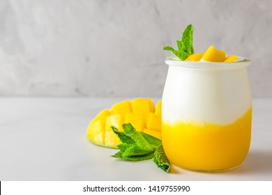 fruit mango yogurt with fresh mint in a glass over concrete background. healthy breakfast. close up