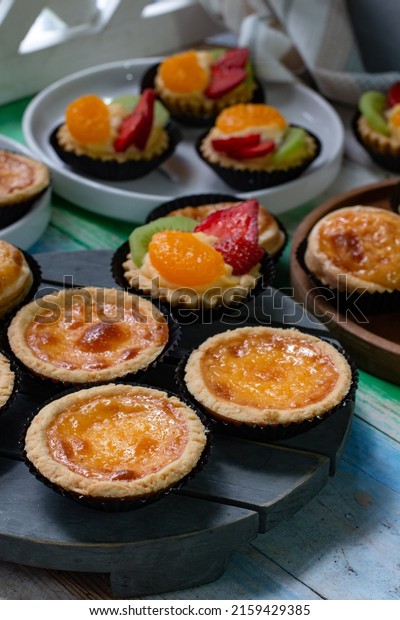 Fruit pies, egg tarts and Portuguese egg tarts on\
wooden board