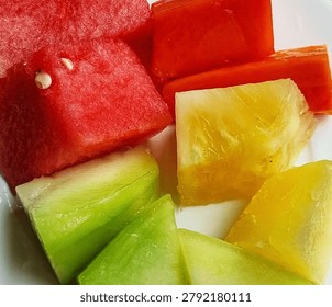 Fruit platter composition featuring slices of watermelon, melon, papaya and pineapple.