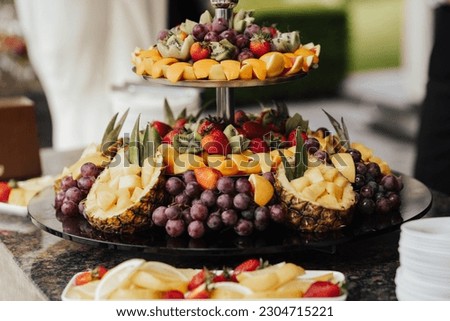 A fruit platter with pineapples, grapes, kiwi, strawberries and oranges on it.