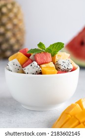 Fruit Salad Bowl With Mango, Watermelon, Dragon Fruit, Pineapple And Mint On A Gray Background, Side View.