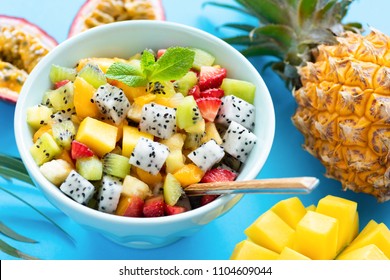 Fruit Salad In Bowl On Blue Background. Exotic Tropical Fruit Salad. Dragon Fruit, Passion Fruit, Mango, Coconut, Strawberry And Pineapple Salad In A Bowl