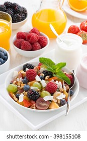 fruit salad in a bowl and various yoghurt, vertical, top view, close-up