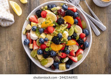 Fruit salad with fresh berries, bananas and apples in a serving bowl with mint and citrus dressing - Powered by Shutterstock