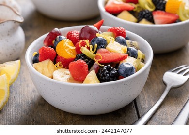 Fruit salad with fresh berries, bananas and apples in small bowls with mint and citrus dressing - Powered by Shutterstock