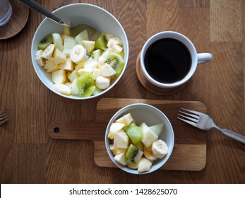 Fruit salad with kiwi fruit, apple, piel de sapo melon and banana in  bowl and a cup of black coffee