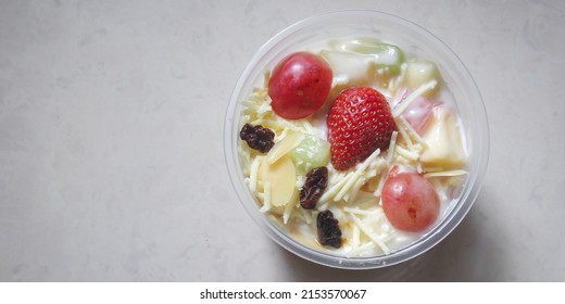 Fruit Salad with Yoghurt or salad buah yogurt on a wooden table. Fruit diet and holiday dessert